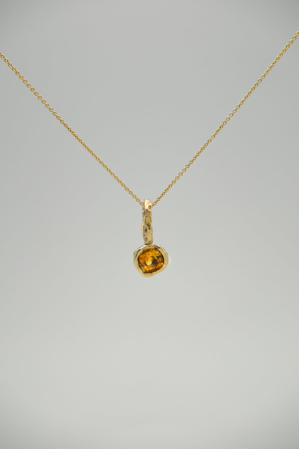 Orange citrine stone pendant from Sol and Mani's June collection, featuring a polished, teardrop-shaped design.
