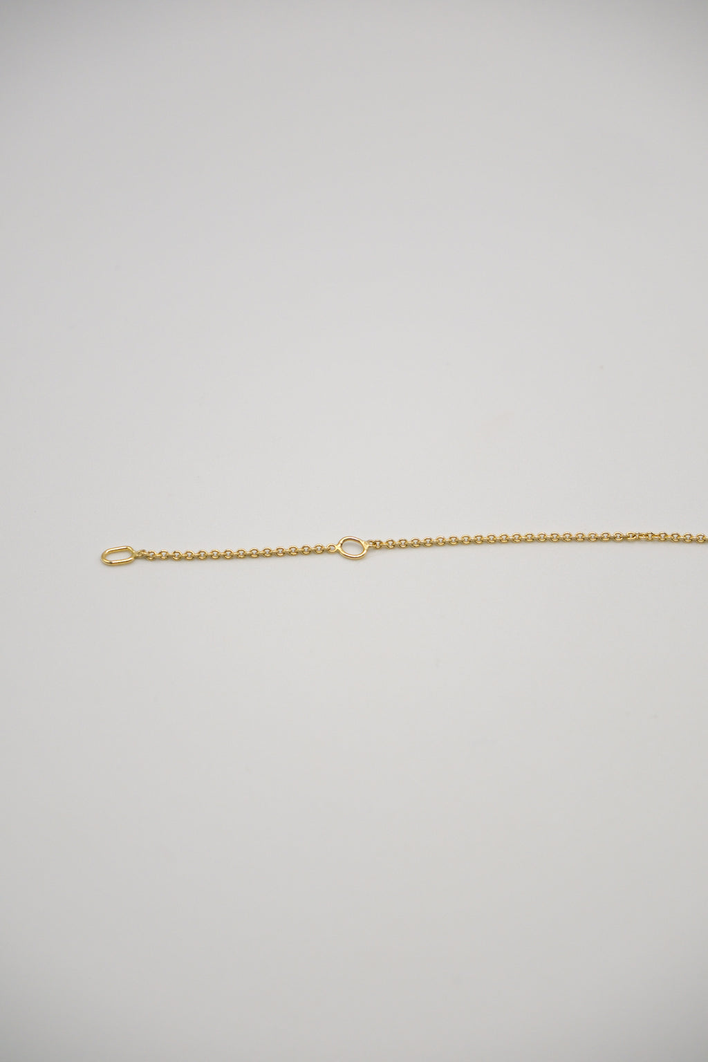 Gold Sol and Mani necklace chain displayed on a white background, showcasing its sleek and shiny jewelry design.