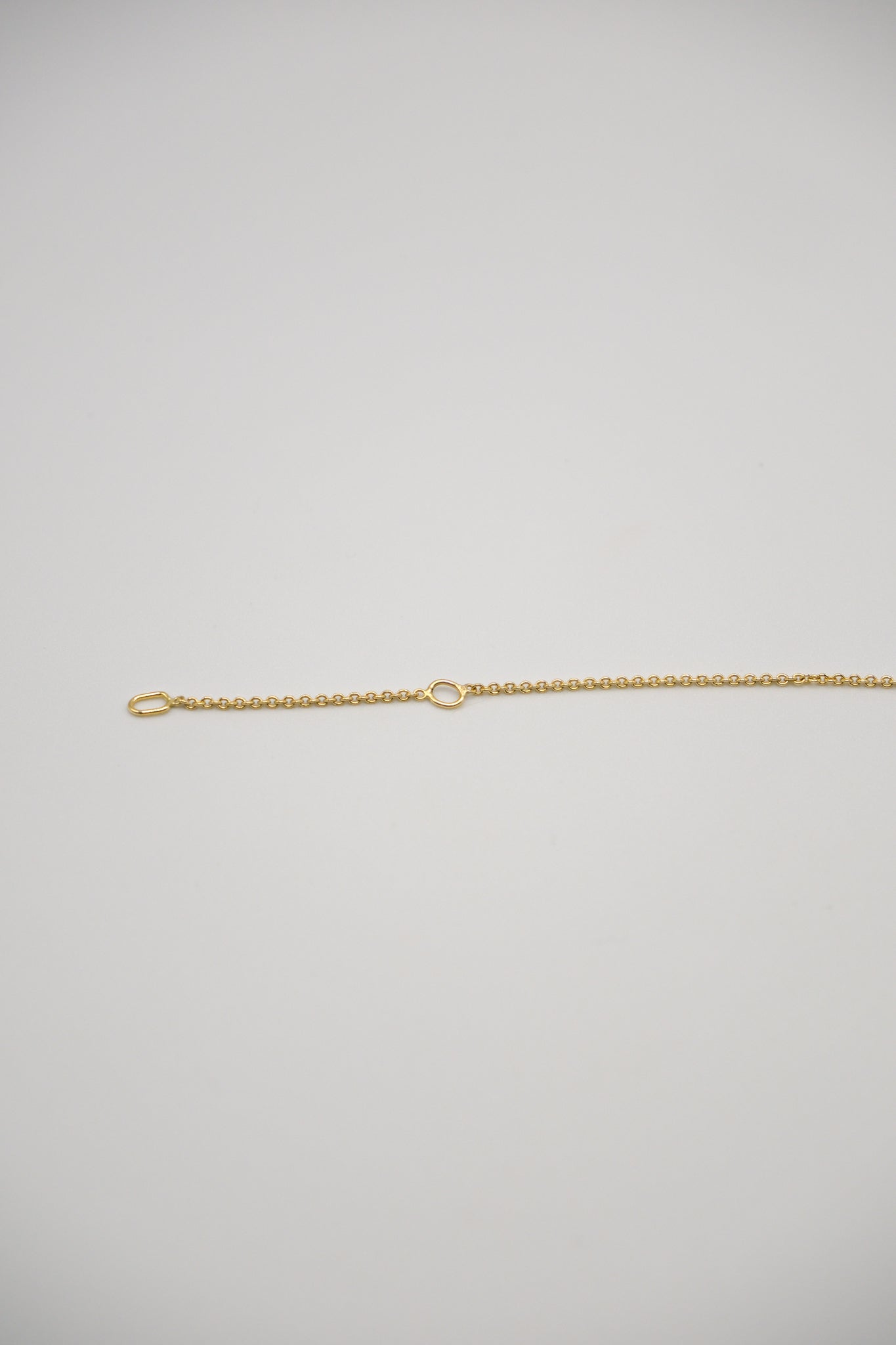 Gold Sol and Mani necklace chain displayed on a white background, showcasing its sleek and shiny jewelry design.
