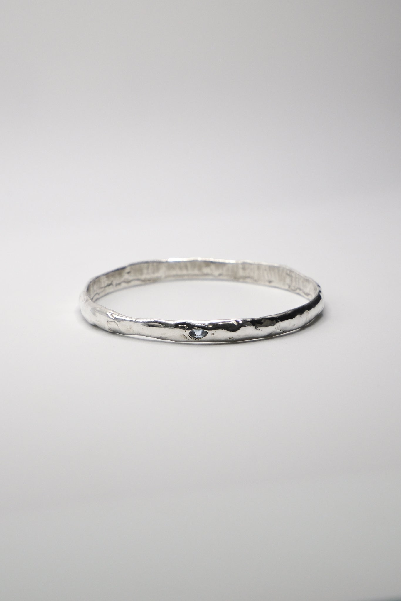 Sol and Mani Moon Bangle featuring a sleek, silver-toned design with a moon-shaped centerpiece and smooth, rounded band.